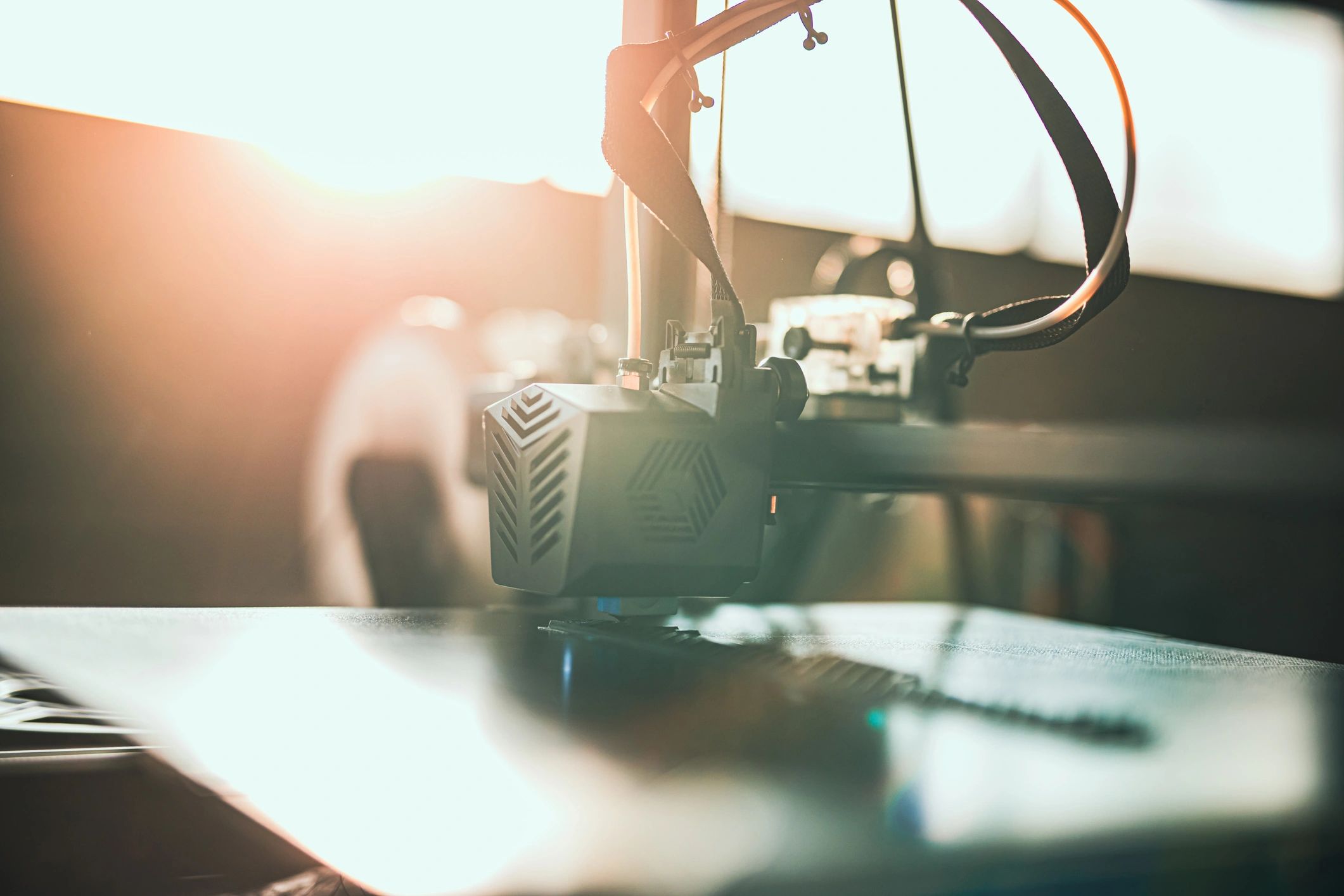 Close-up of a 3D printer head printing in warm light