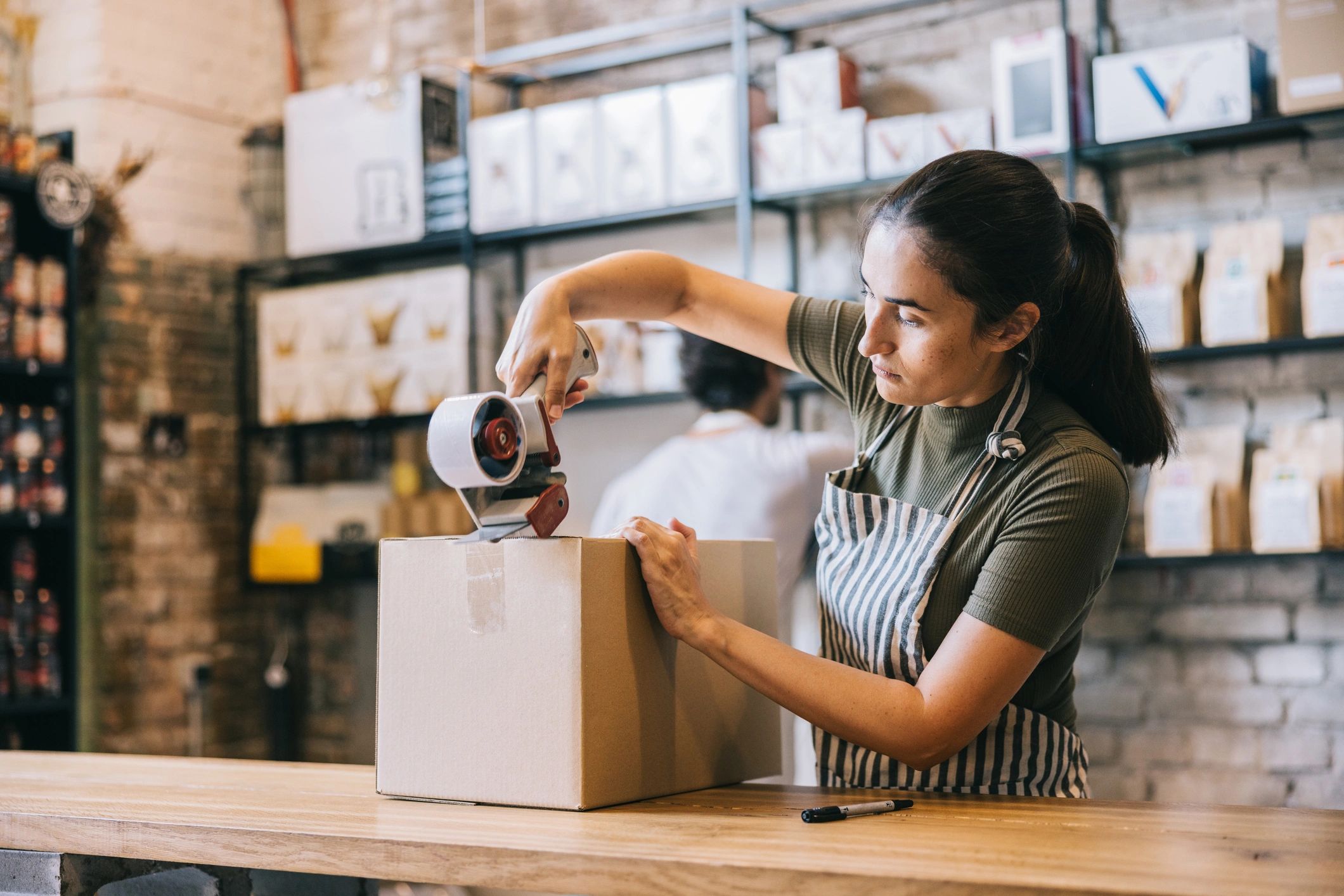 Small business owner taping a shipping box closed